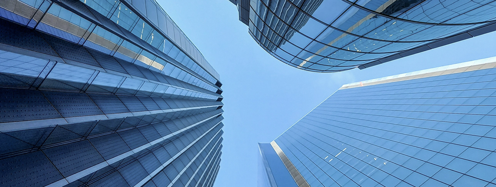 Upward view of modern glass skyscrapers with curved facades against a blue sky